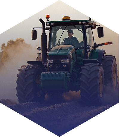 Tractor verde trabajando en campo polvoriento al atardecer